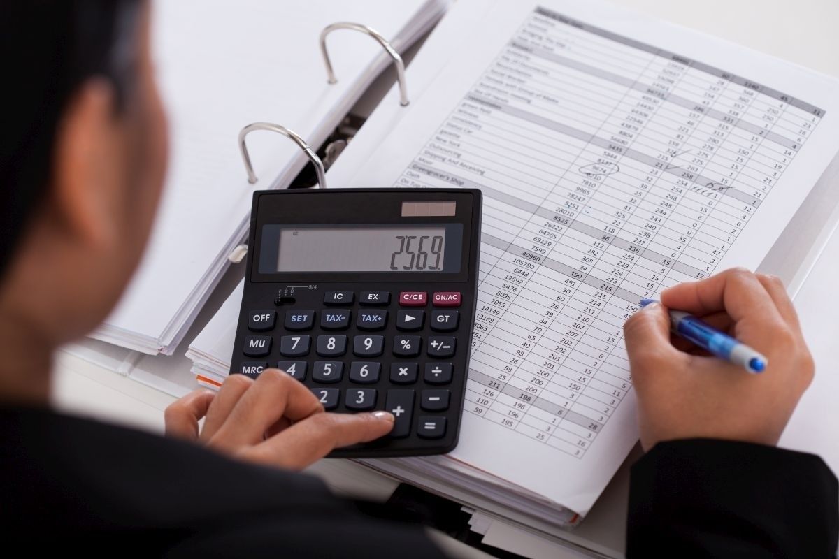 Foto de uma pessoa usando uma calculadora e anotando em um papel, representando contratar um contador