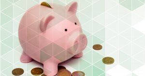 Imagem de um cofrinho em forma de porco com algumas moedas a sua volta, representando as formas de economizar nos impostos