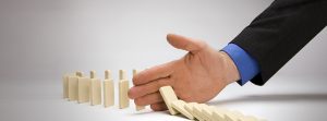 Foto de uma mão segurando uma sequencia de dominós, representando o empreendedorismo na crise econômica