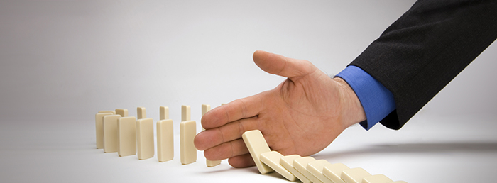 Foto de uma mão segurando uma sequencia de dominós, representando o empreendedorismo na crise econômica