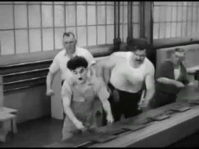 Cena do filme Tempos Modernos, onde Charles Chaplin aperta algumas peças, em representação da produção e produtividade