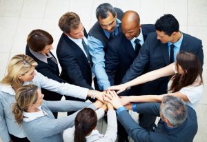 Foto de muitas pessoas com as mãos juntas, representando a gestão de pessoas nas PMEs