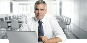 Foto de um homem sentado a uma mesa mexendo no computador, representando abrir mei pela internet