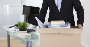 Foto de um homem carregando uma caixa com coisas de escritório representando as dicas para dispensar um funcionário