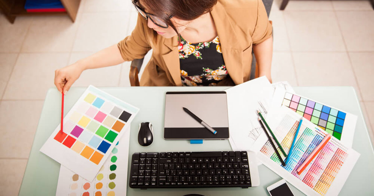 Foto e uma mulher designer, consultando uma paleta de cores, representando a criação de um logotipo
