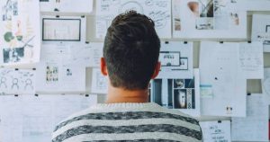 Foto de um homem de costas, olhando para um quadro cheio de papeis, representando os mitos sobre empreendedorismo