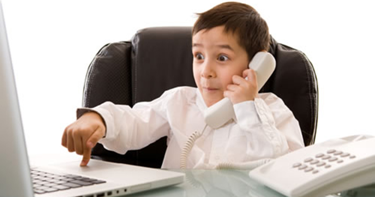 Foto de um menino falando ao telefone e mexendo em um notebook, representando as lições de crianças