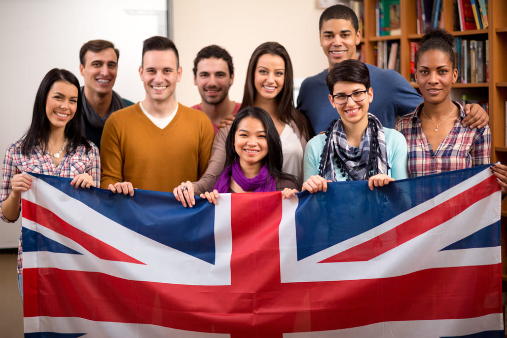 Foto de alguns alunos segurando a bandeira do Reino Unido, representando como abrir uma escola de idiomas