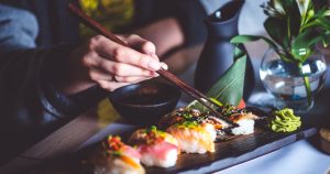 foto de uma pessoa comendo sushi com palitos, representando como abrir um restaurante japonês