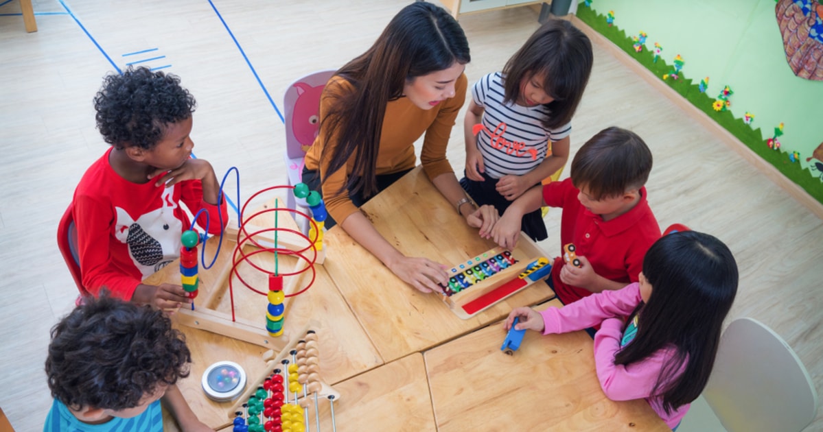 foto de uma mulher e várias crianças brincando, representando como abrir uma brinquedoteca