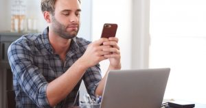 foto de um homem mexendo no celular enquanto trabalha, representando como parar de procrastinar