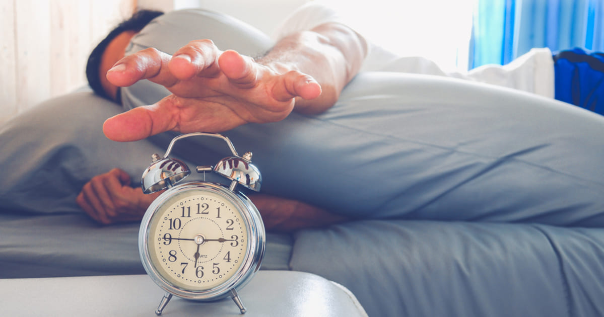 foto de um homem apertando um relógio, representando as dicas para acordar melhor