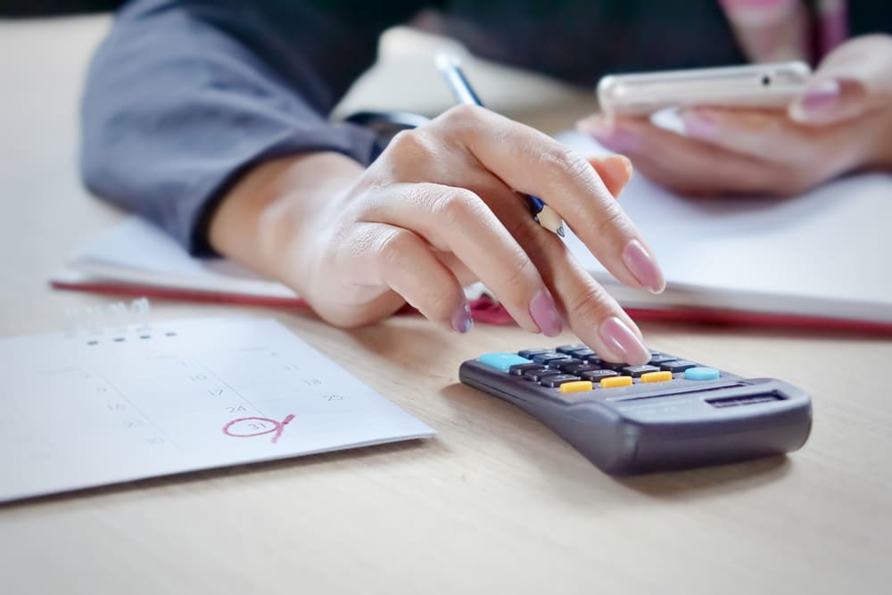 foto de uma mulher digitando em uma calculadora, representando como abrir empresa com nome sujo