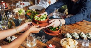 foto de pessoas comendo em uma mesa com pratos de refeições, representando como abrir um restaurante vegetariano