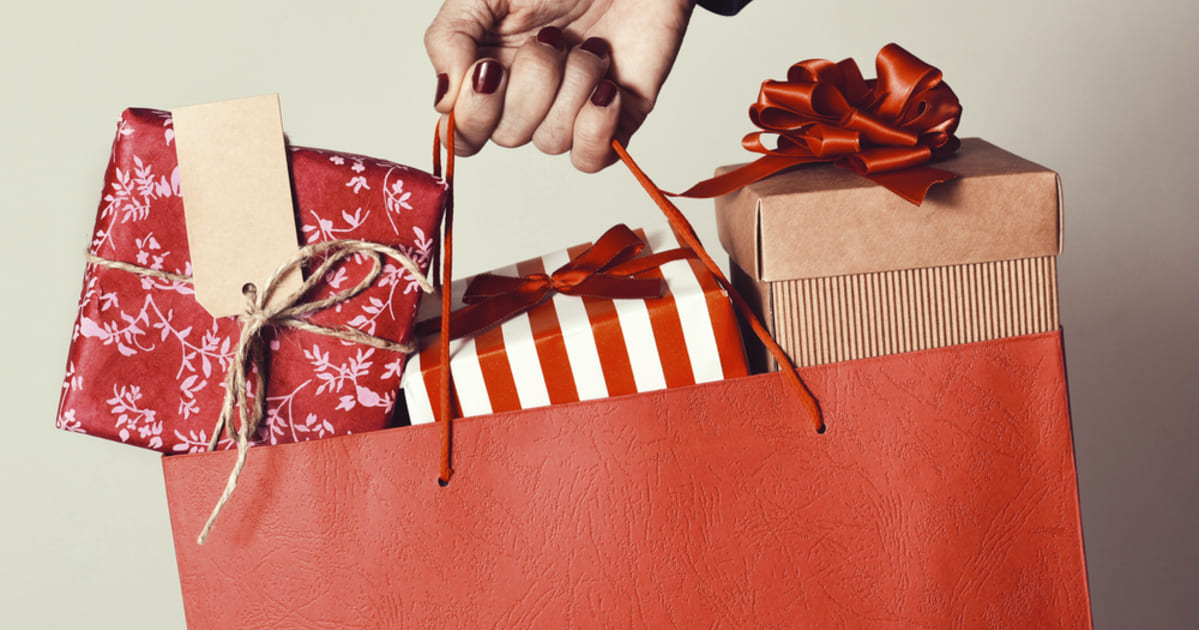 foto de uma mão feminina segurando uma sacola com presentes, representando a sazonalidade de vendas