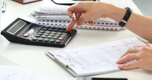 foto de uma pessoa mexendo em calculadora e fazendo os cálculos do IRPF 2019