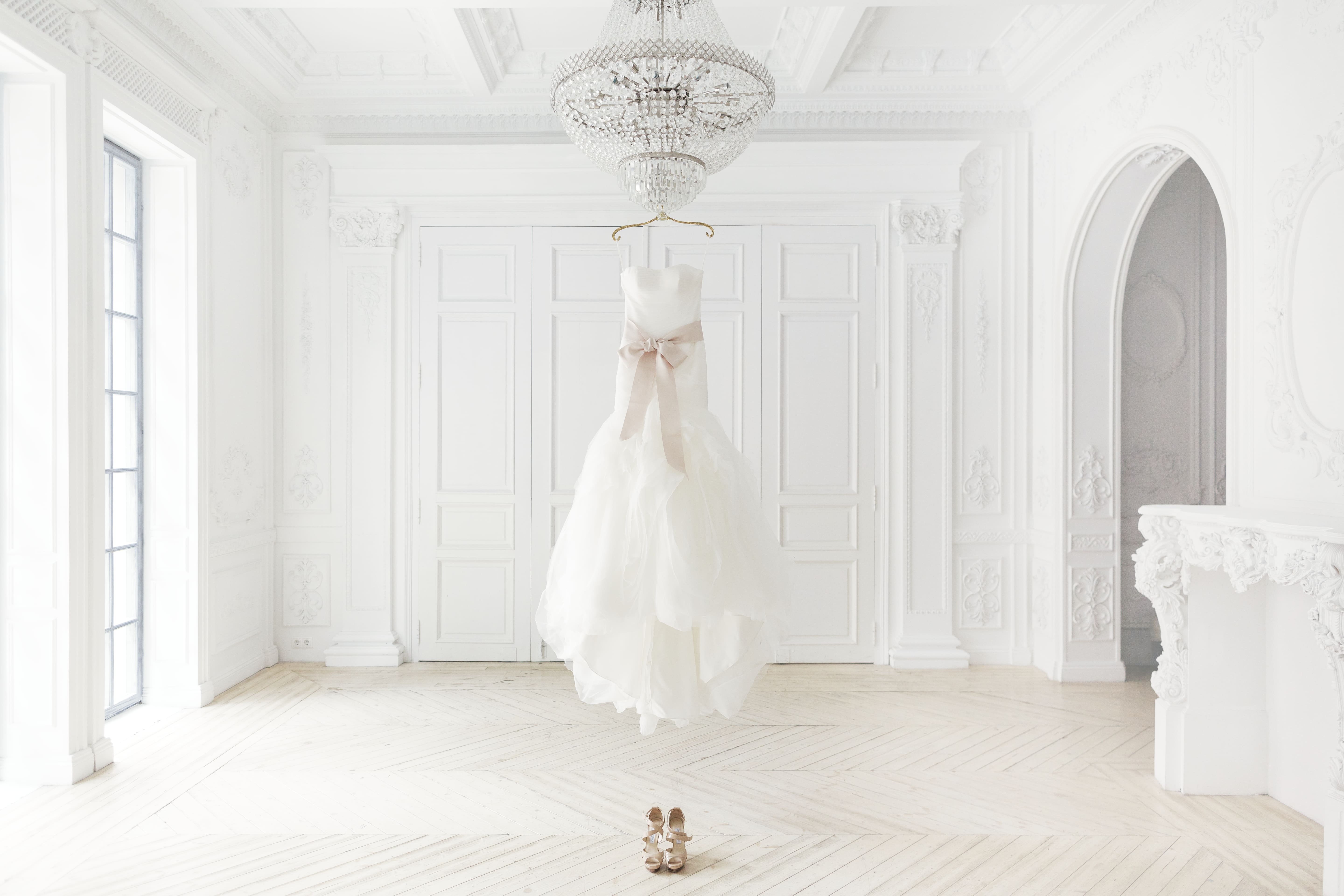 Imagem de um vestido de noiva pendurado no meio de um espaço de um ateliê depois que um empreendedor resolveu abrir uma loja de confecção de vestidos de noiva
