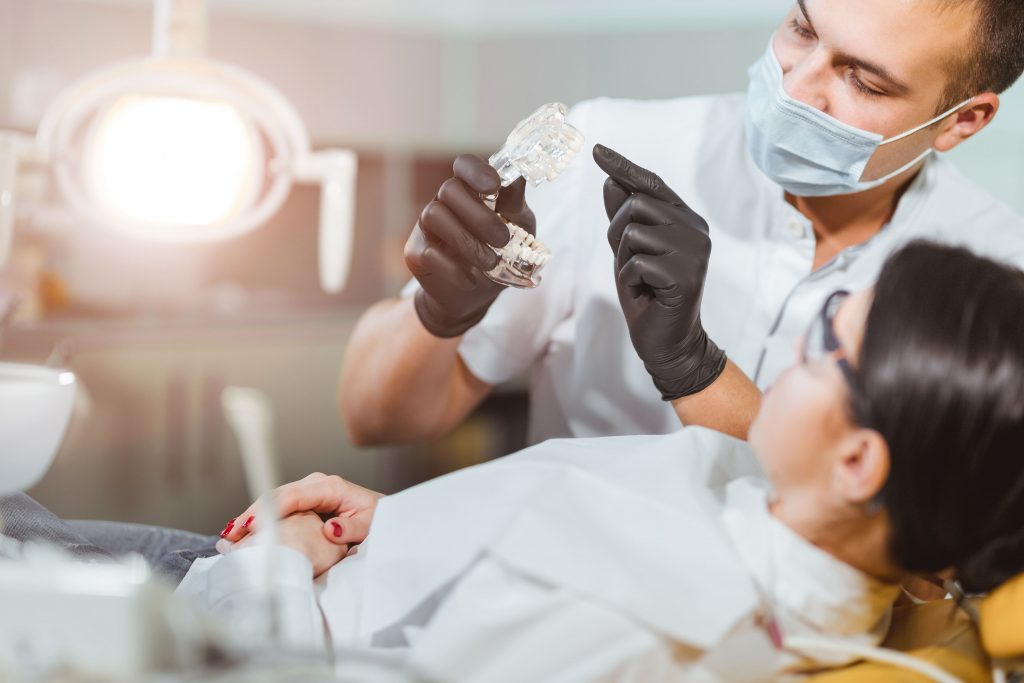 Imagem de um dentista atendendo uma paciente depois que ele decidiu abrir uma clínica odontológica