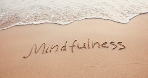 Imagem de uma praia que na areia está escrito a palavra mindfulness