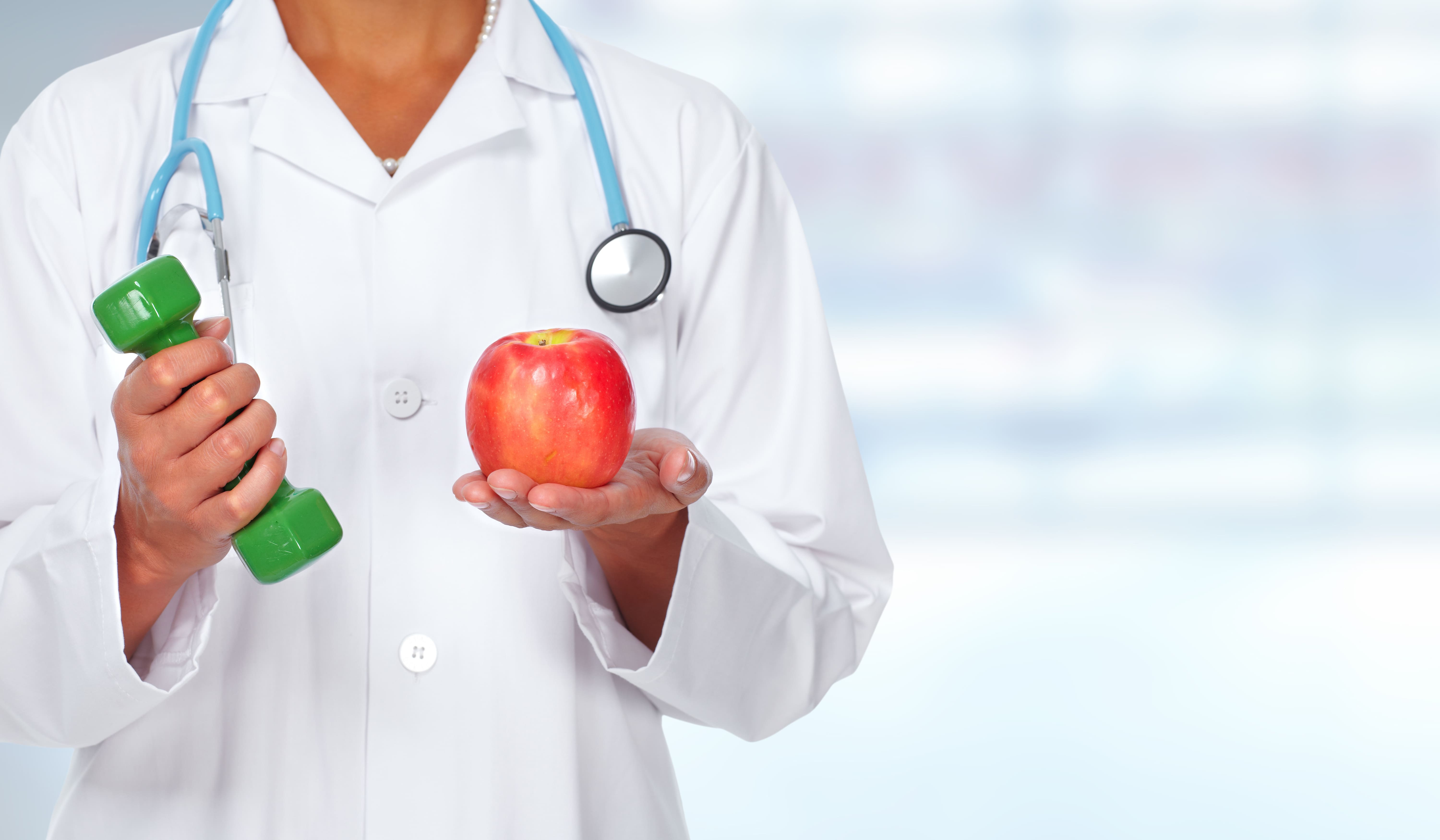 Imagem de um médico segurando um peso e uma maçã para remeter ao empreendedor que deseja abrir uma clínica de saúde esportiva